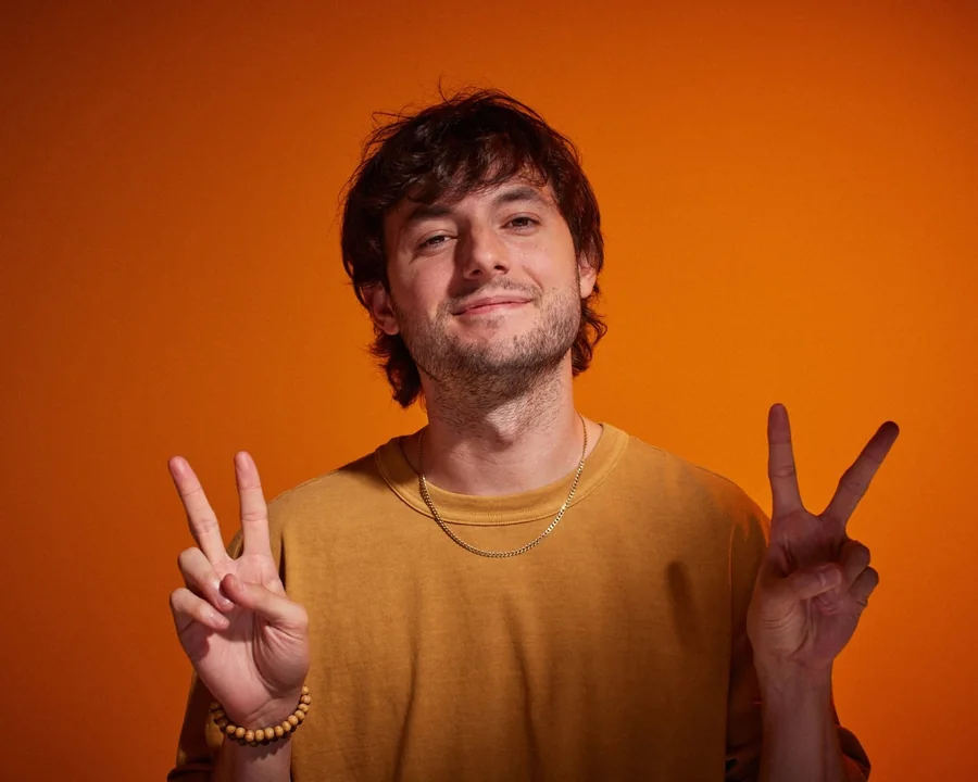 Wesley Elder flashing two peace signs against an orange backdrop.
