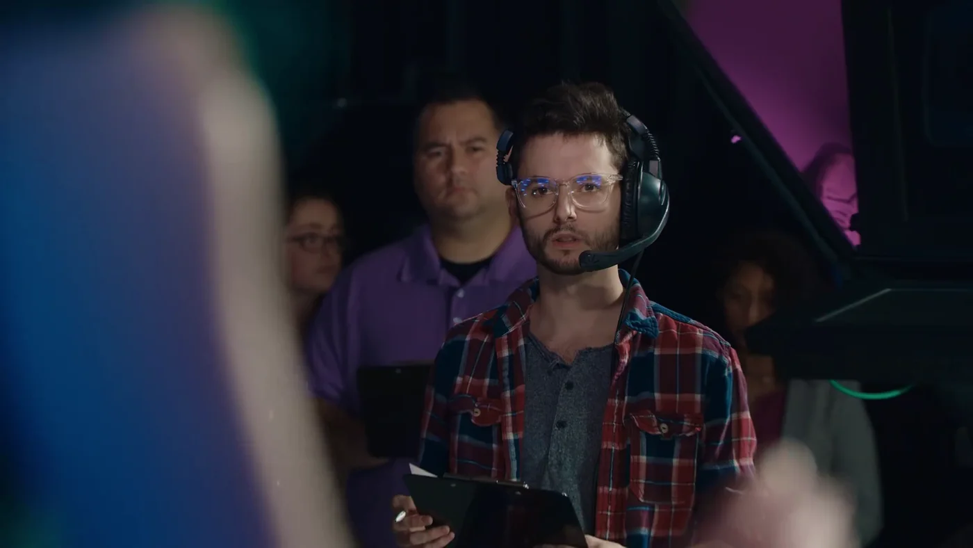 A man wearing a headset watches from a control room in Bad News.
