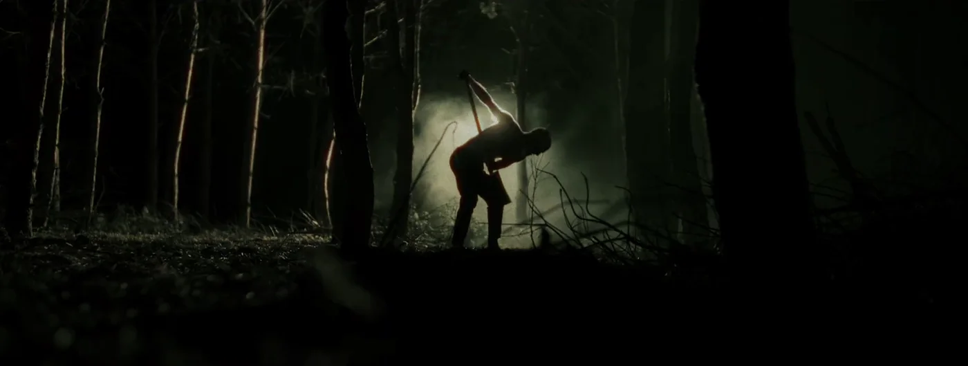 A backlit figure digs in a dark, smoky forest in Justice for Peanut.