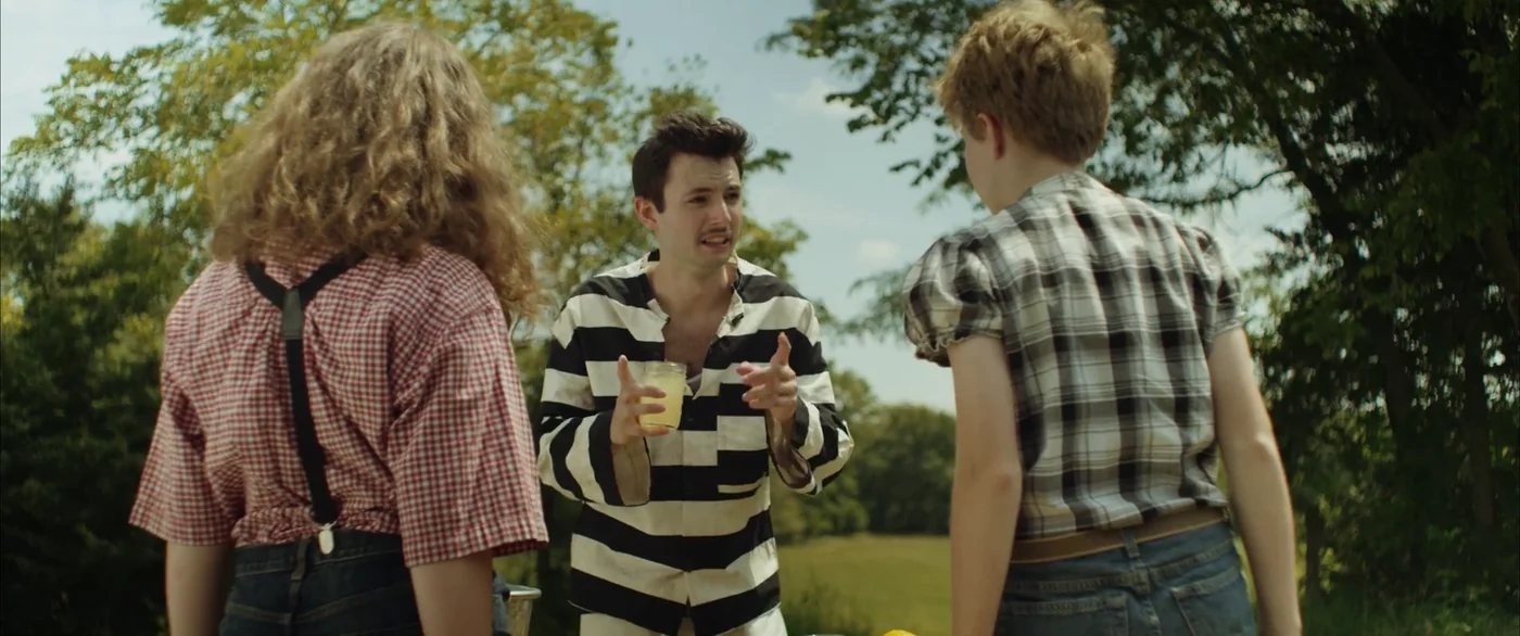 The man in stripes gestures with a cup of lemonade as the two children listen in The Escape of Tina Kleinfelder.