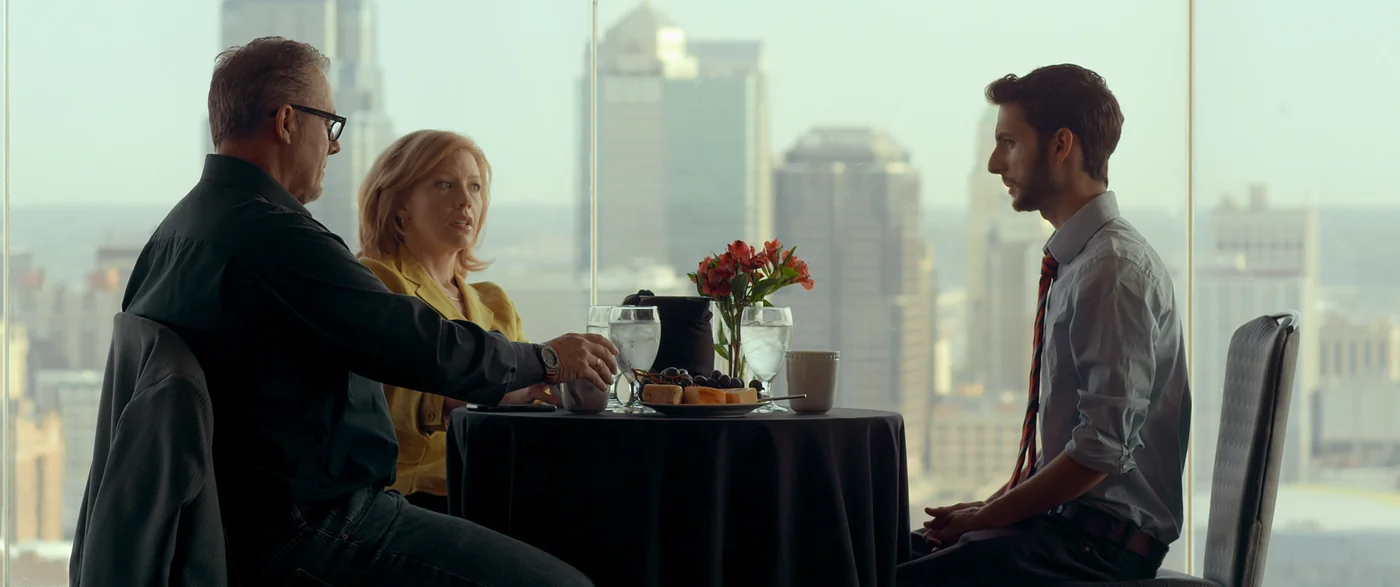 Three people talk at a table overlooking the city in The Matchbreaker.